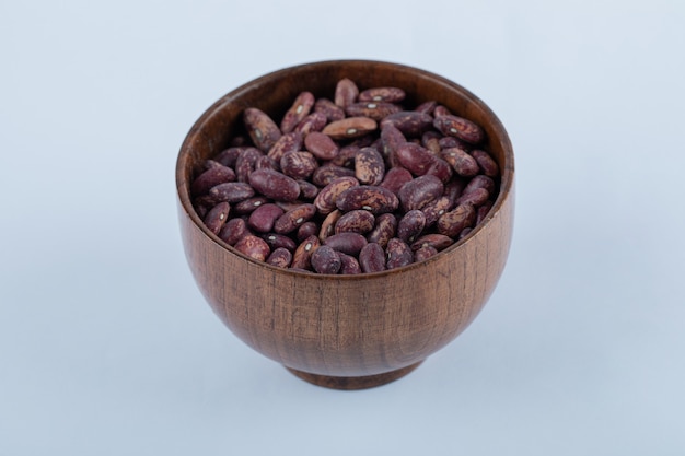 A small wooden bowl full of raw red kidney beans.