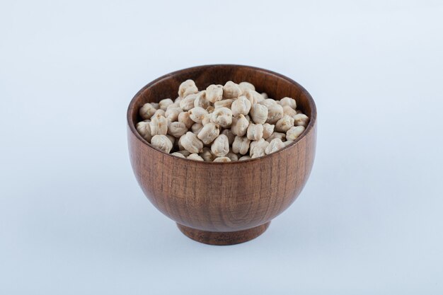 A small wooden bowl full of raw white peas beans