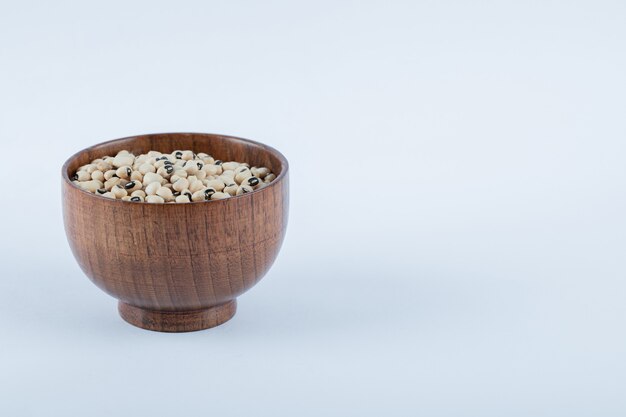 A small wooden bowl full of raw white peas.