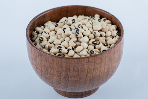 A small wooden bowl full of raw white peas.