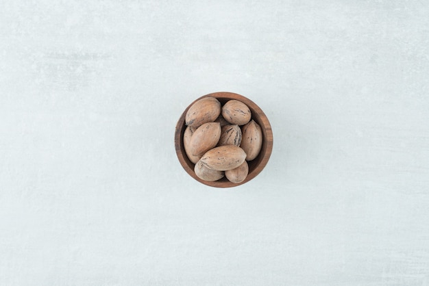Небольшая деревянная миска с орехами на белом фоне. Фото высокого качества