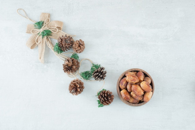 A small wooden bowl of nuts with pinecones on white background. High quality photo