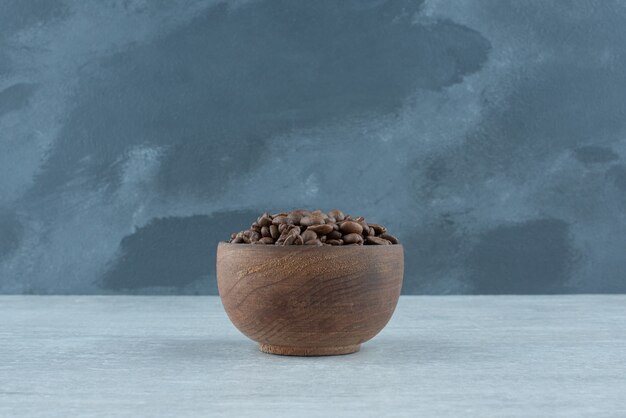 A small wooden bowl with coffee beans on white background. High quality photo