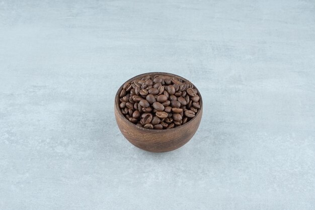 A small wooden bowl with coffee beans on white background. High quality photo