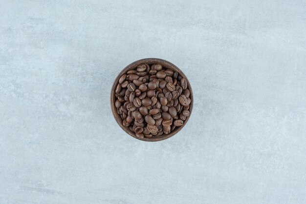 Free photo a small wooden bowl with coffee beans on white