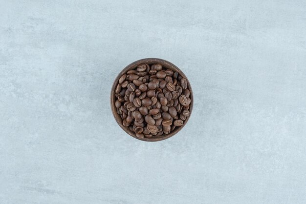 A small wooden bowl with coffee beans on white