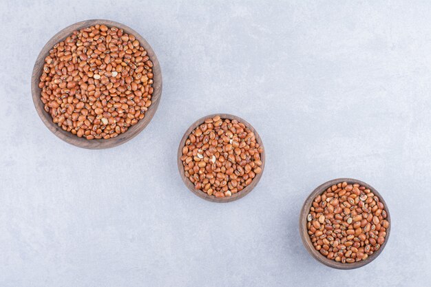 Small wooden bowls full of red beans on marble surface