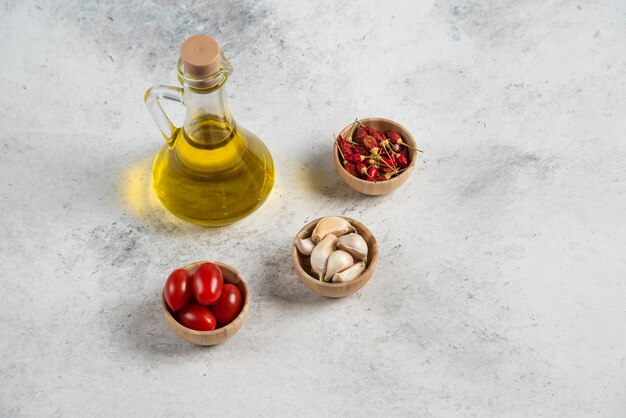 Маленькие деревянные миски с овощами и оливковым маслом на мраморном фоне.