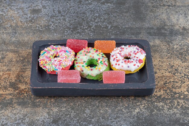 A small, wooden platter with bite-sized donuts and marmelades on wooden surface