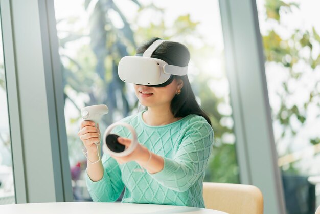 Smart attractive asian female business owner weared virtual reality glasses enjoys casual metaverse meeting with concentrate at cafe restaurantasian female using oculus rift headset in cafe