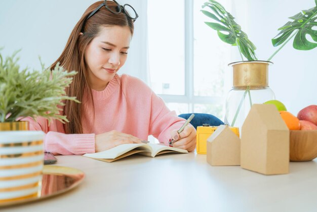 Smart beautiful casual asian woman enjoy reading book weekend in pink sweater home background