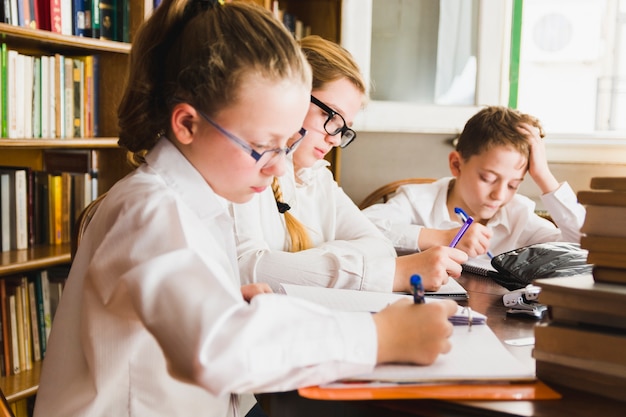 Free photo smart children writing sitting in library