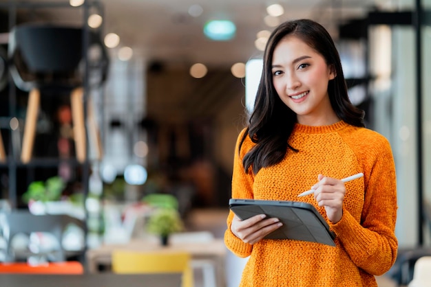 Smart confidence asian female startup entrepreneur small business owner businesswoman wear smart casual cloth smile hand use tablet woking inventory checking in showroom office daytime background