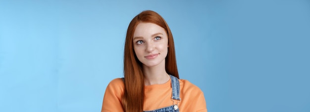 Free photo smart creative pretty redhead female freelancer thoughtfully look upper left corner pondering