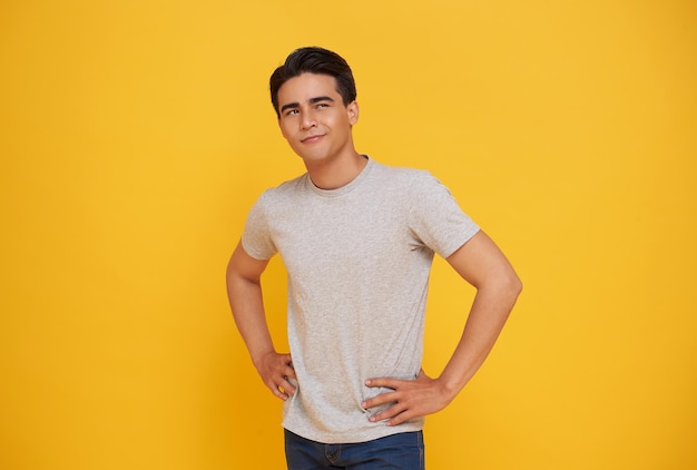 Free photo smart handsome young asian man thinking while looking up isolated on colorful yellow background