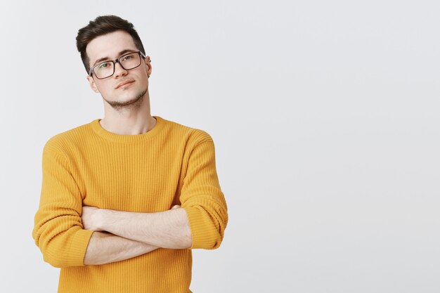 Smart man in glasses cross hands over chest and looking confident