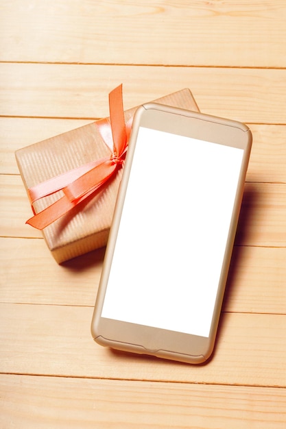 Free photo smart phone and gift on wooden background