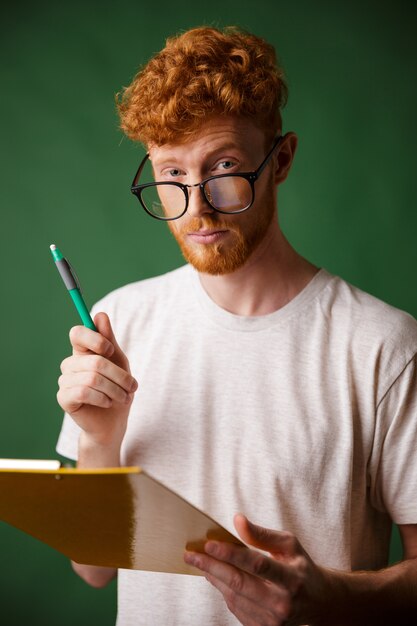Smart readhead bearded man in white tshirt holding folder and pen,