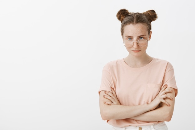 Smart serious-looking teenage girl posing against the white wall