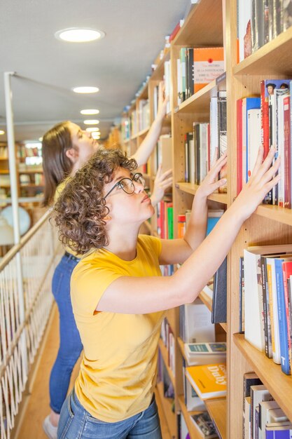 Smart teenager looking for book near friend