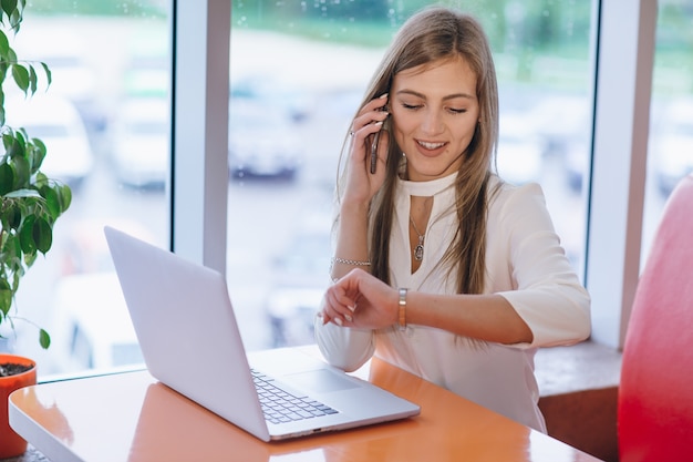 Smart woman talking on the phone and looking at the time