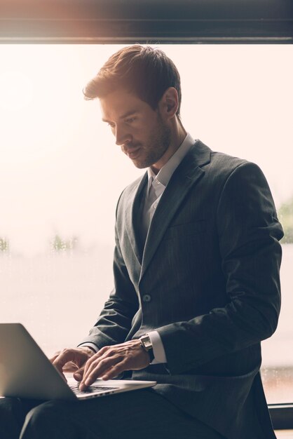 Smart young businessman typing on laptop