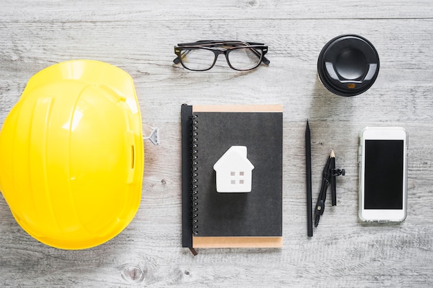 Smartphone and beverage near hardhat and stationery