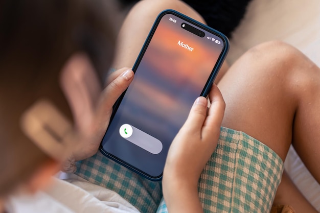 Foto gratuita smartphone nelle mani del bambino con la chiamata della madre in arrivo su uno schermo