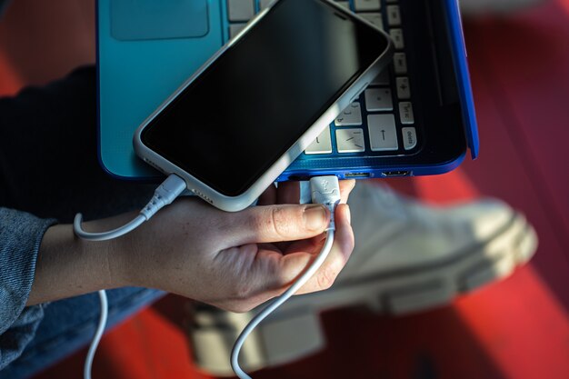 Смартфон, подключенный к ноутбуку с помощью USB-кабеля, зарядка телефона, обмен данными.