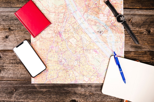 Smartphone, diary, notepad, map and wrist watch on wooden table