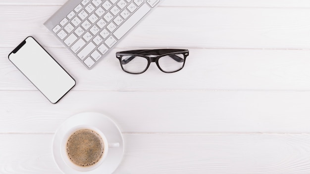 Smartphone, eyeglasses, cup and keyboard