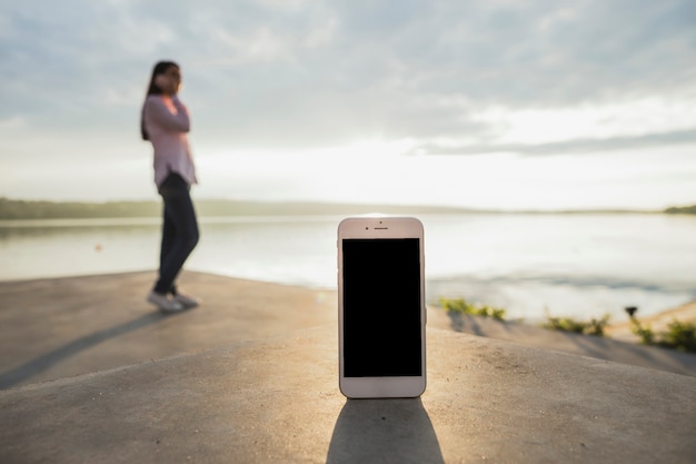 Смартфон перед женщиной, говорить на сотовый телефон, стоя рядом с озером