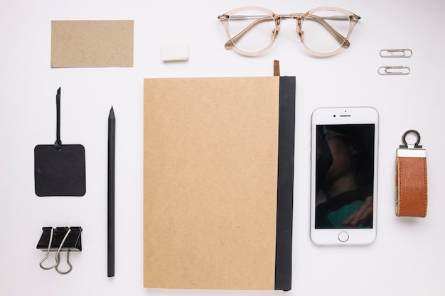 Smartphone and glasses near closed notepad