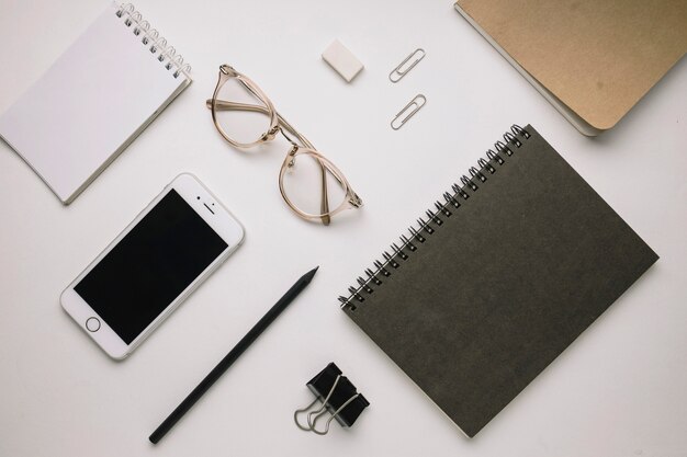 Smartphone and glasses near notebooks