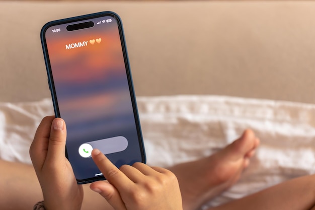 無料写真 子供の手にあるスマートフォンと画面にママからの電話がかかってくる