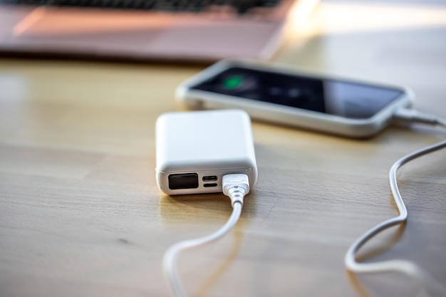 A smartphone is charged from a small white power bank