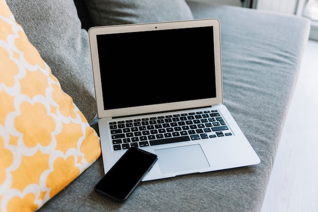 Smartphone and laptop on couch