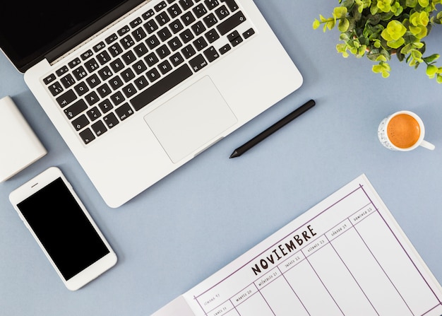 Smartphone and laptop with notebook on blue table