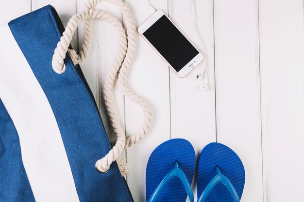 Smartphone near flip-flops and bag