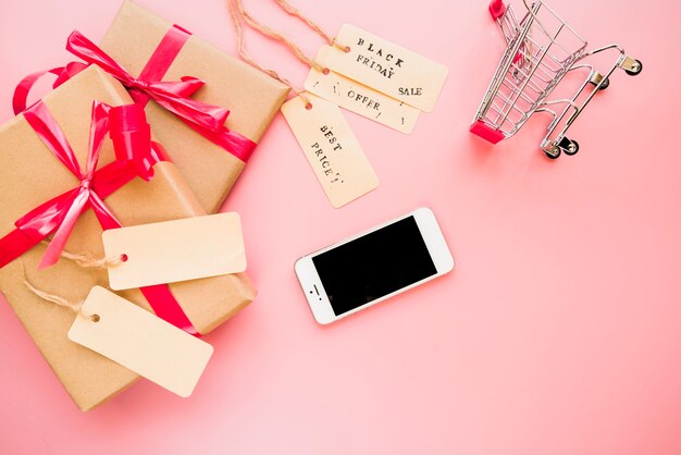 Smartphone near shopping trolley and present boxes