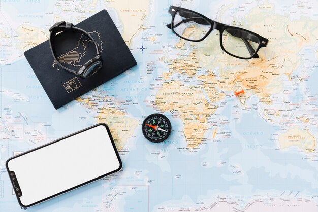 Smartphone; passport; wrist watch; compass and eyeglasses on world map