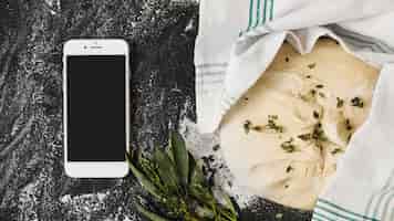 Foto gratuita smartphone; pasta cruda; thymes sul piano di lavoro della cucina
