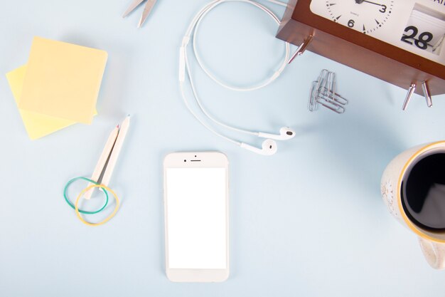 Smartphone and stationery near clock and coffee