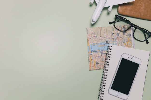 Smartphone and travel supplies on green