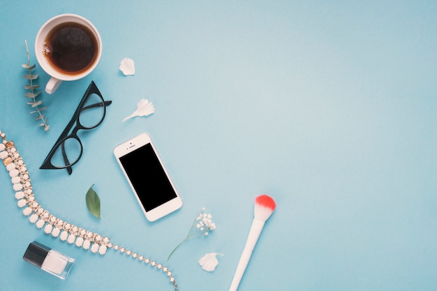 Smartphone with glasses, tea cup and flowers