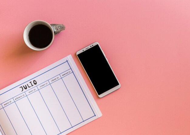 Smartphone with notebook and coffee on table