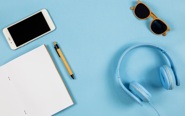 Smartphone with notebook and headphones on table