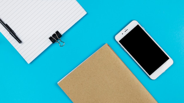 Smartphone with notebook on table 