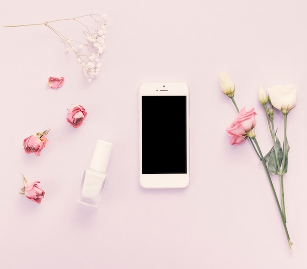 Smartphone with roses and nail polish on table