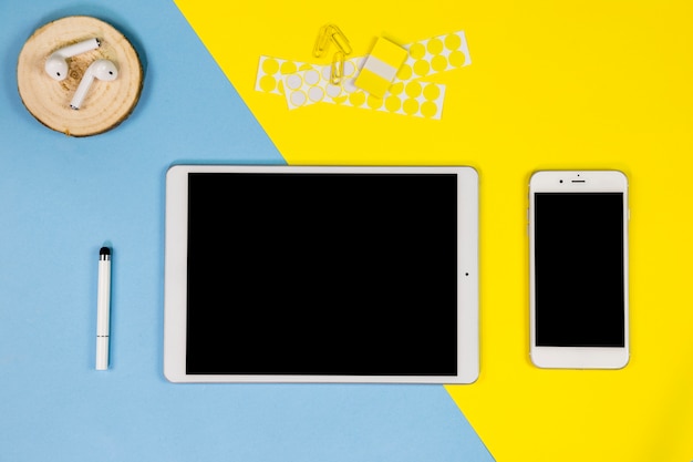 Smartphone with tablet and earphones on table